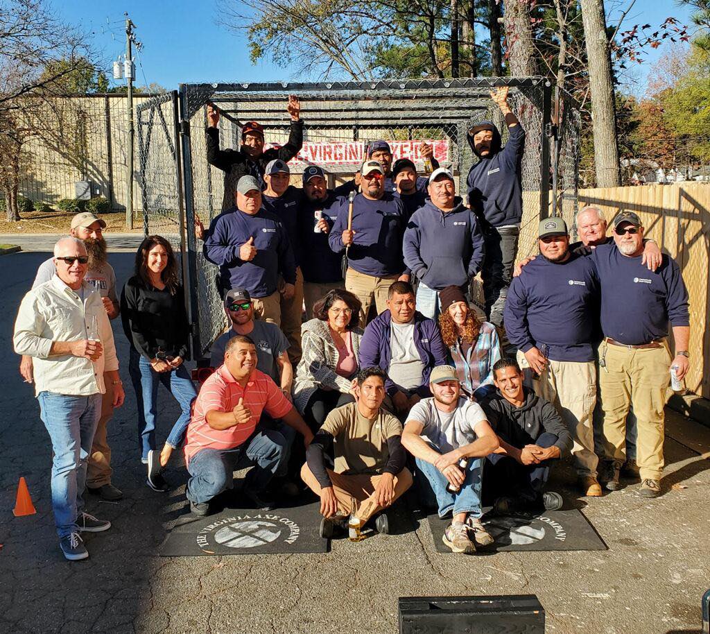 A twenty-person work crew posed at the cage in matching shirts
