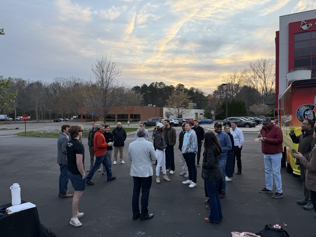 Guests mingling at dusk by a food truck under a spectacular sky