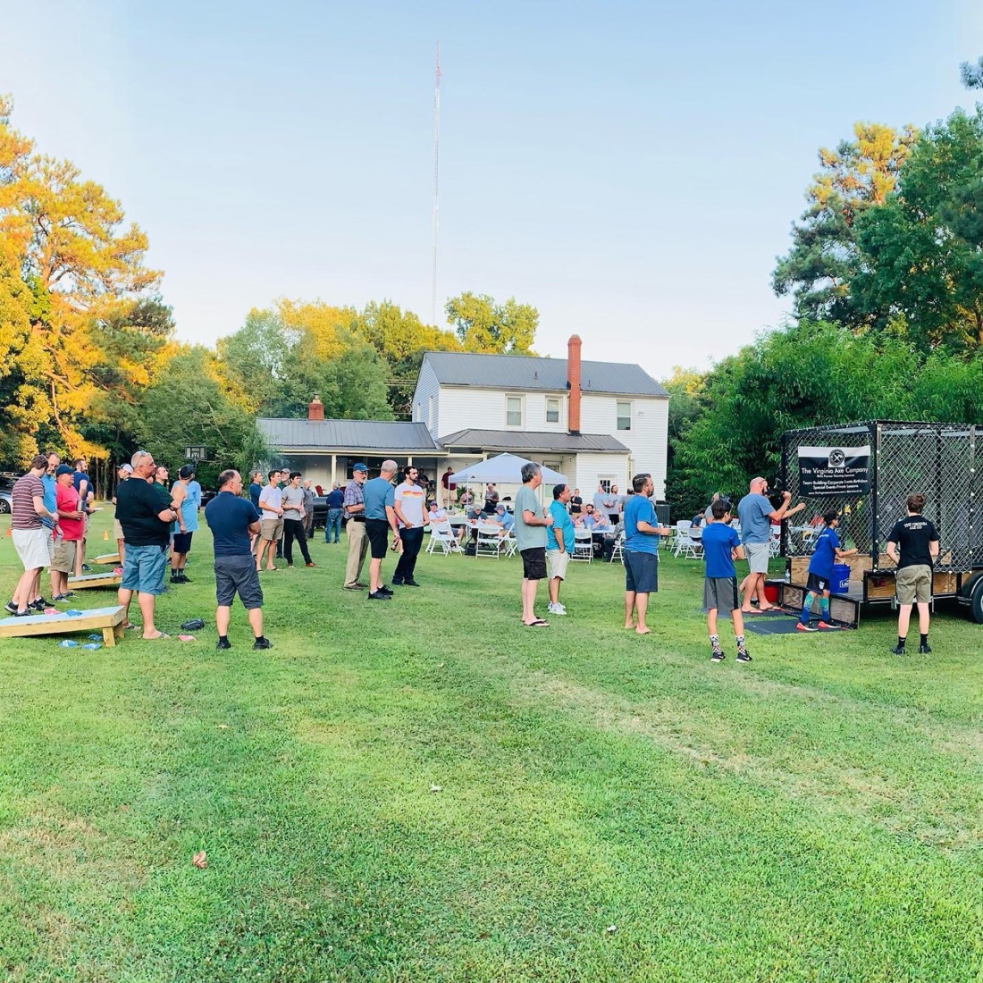 A golden-hour backyard party with cornhole beside the range